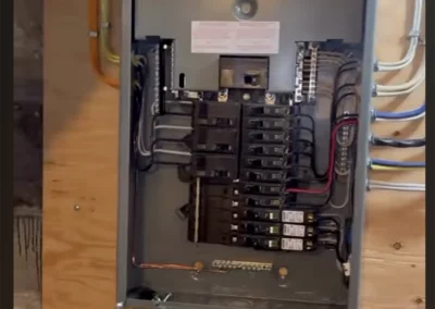 Open breaker panel wired in a wood-framed wall