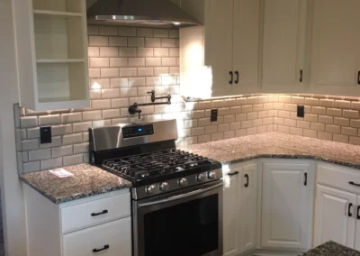Kitchen with recessed lights over a range and white cabinets