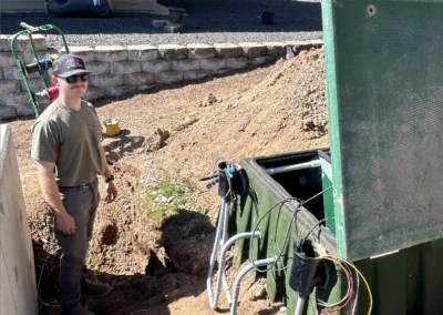 Electrician by a trench with conduit and a green utility transformer