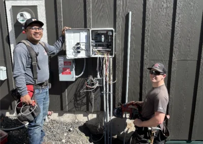 Electricians wiring meter bases on a new building exterior