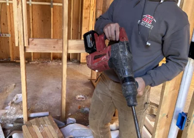 Smiling electrician in a cap holding a drill in a framed house