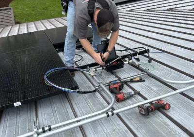 Electrician mounting solar panel rails on a metal roof